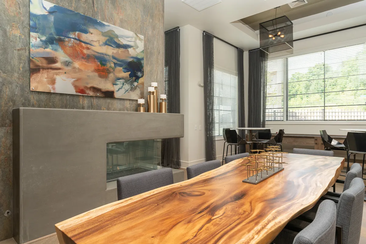 A spacious dining area highlighted by a large wooden dining table, contemporary wall art, and a minimalist fireplace. The setting is sophisticated yet relaxed, perfect for hosting dinners and gatherings.
