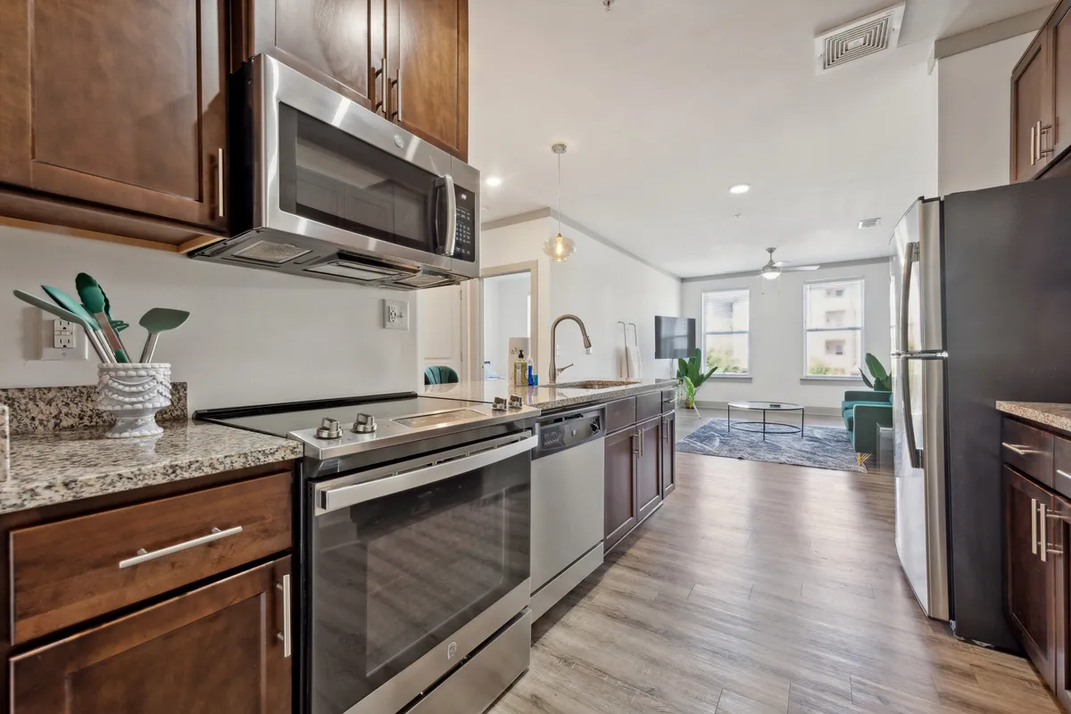 A contemporary kitchen featuring sleek stainless steel appliances, granite countertops, a modern faucet, and large windows that flood the space with natural light. The layout encourages gatherings and culinary creativity.