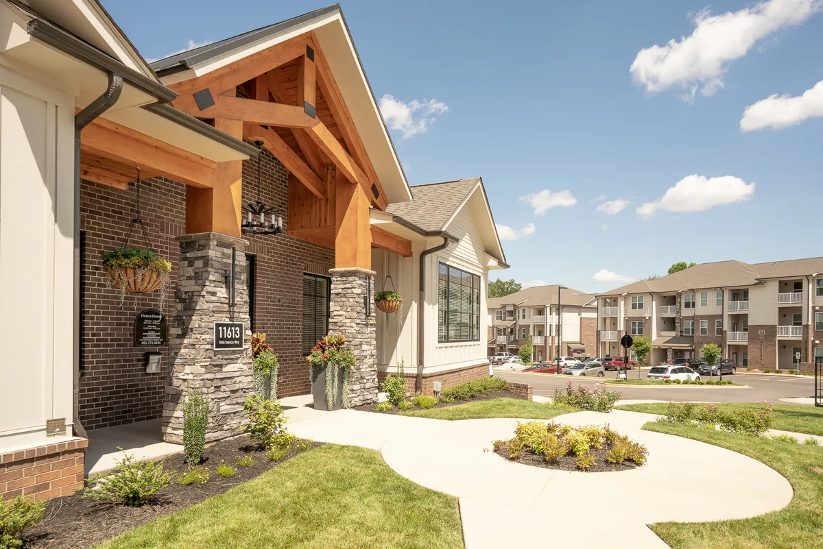 This image captures the entrance of the property, featuring warm wooden beams, a stone facade, and a lush landscaped garden. The setting radiates a welcoming and safe neighborhood atmosphere, reinforcing the sense of peace and comfort described in the section.