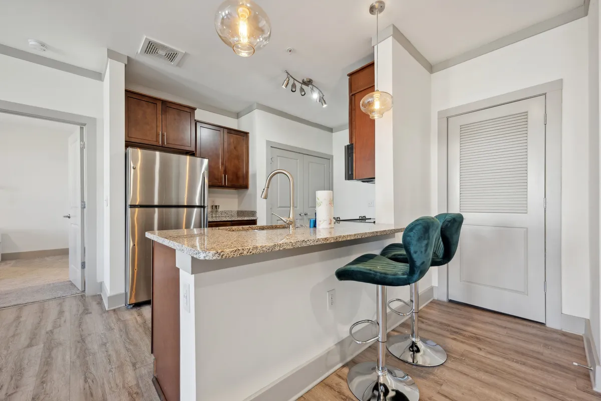 A sleek kitchen with granite countertops, bar stools, stainless steel appliances, and stylish pendant lights. The space is designed for both culinary creativity and casual dining, supporting a variety of social and family activities.